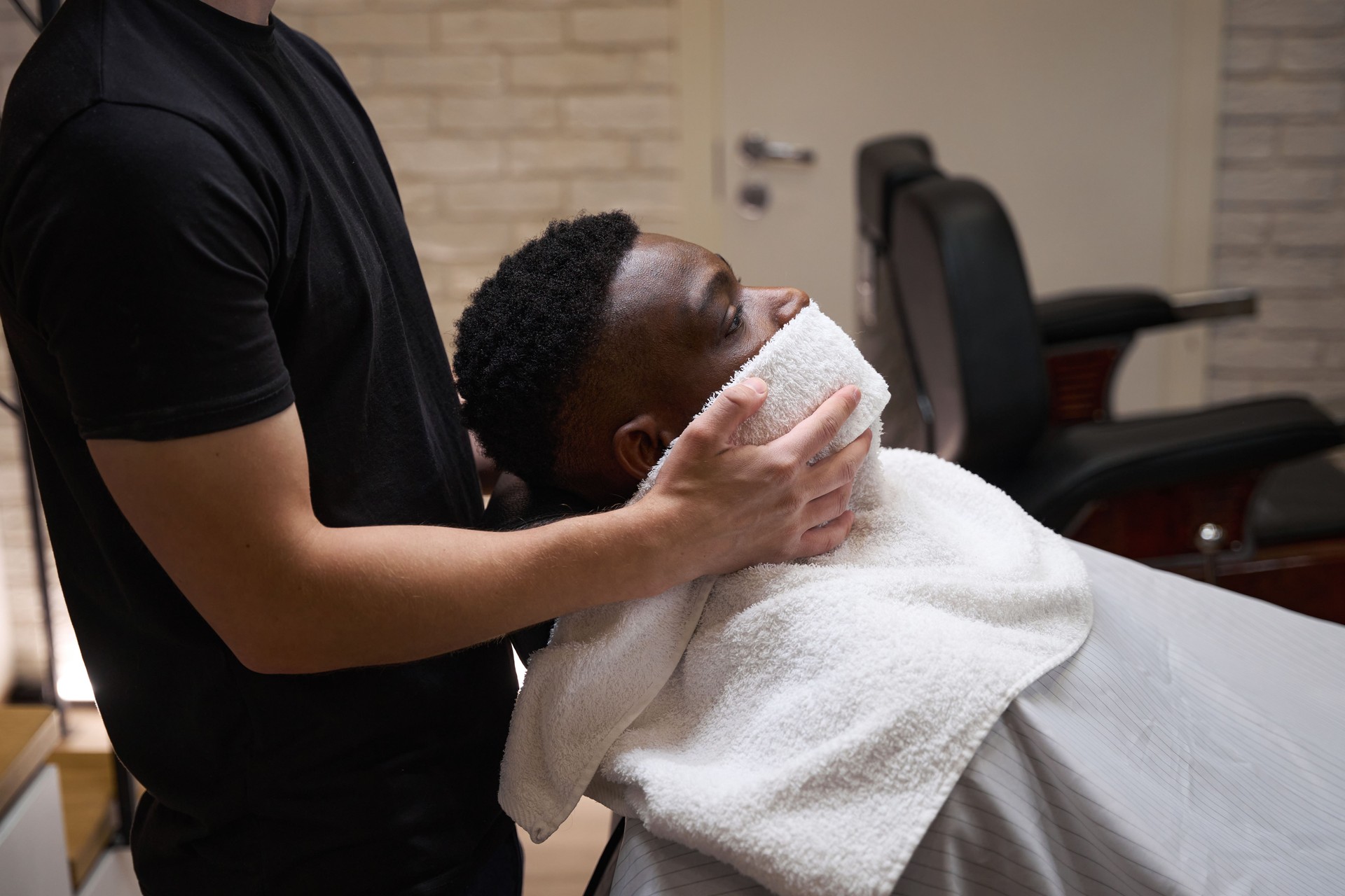 African American guy sits in a barbershop in barber chair